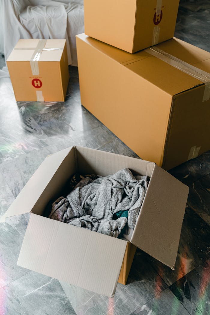 services-02 From above of cardboard boxes with packed items placed on floor in new apartment