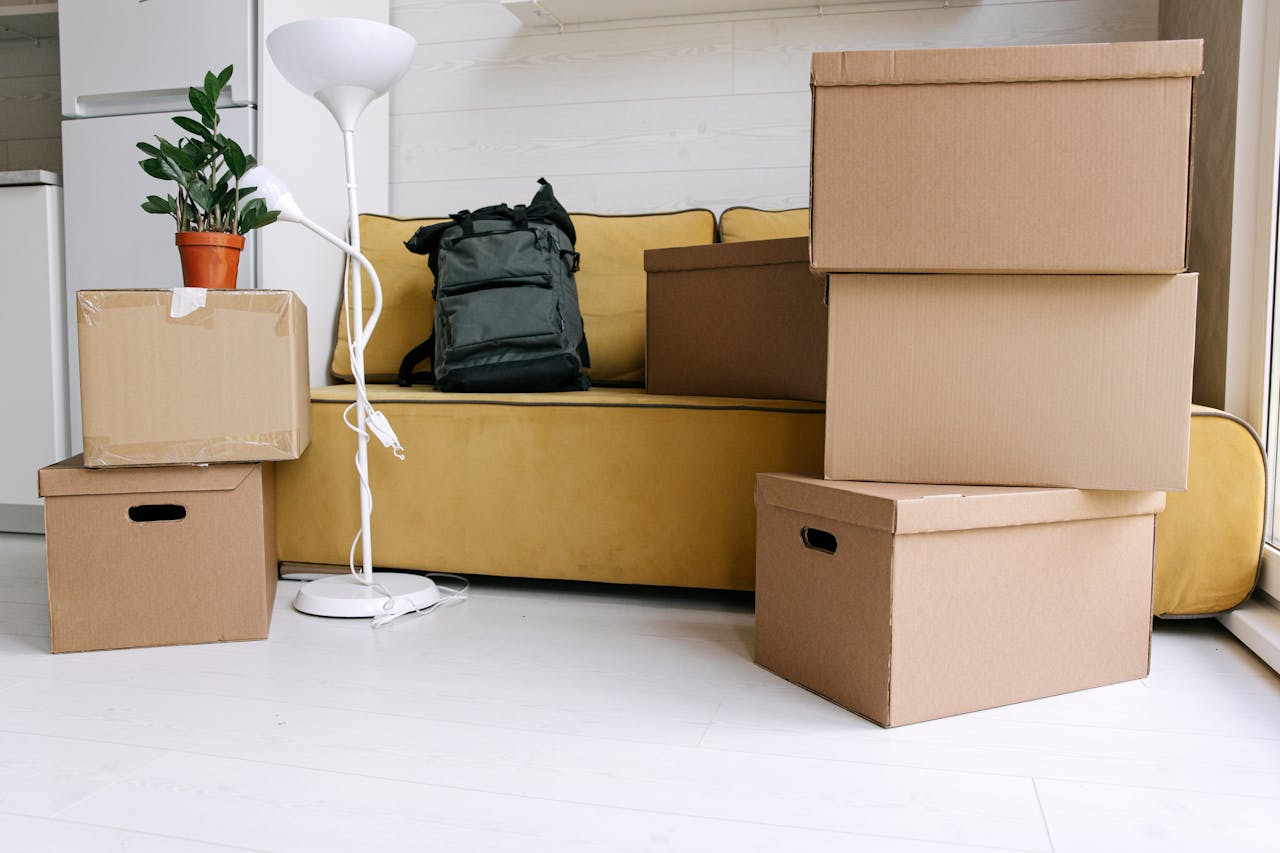 services-04 Cardboard boxes and a backpack in a cozy living room signify moving day excitement.