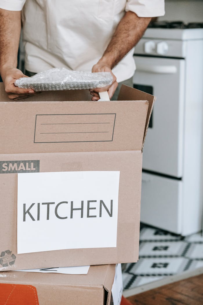 hero-img Man packing kitchenware into labeled boxes for a home relocation.